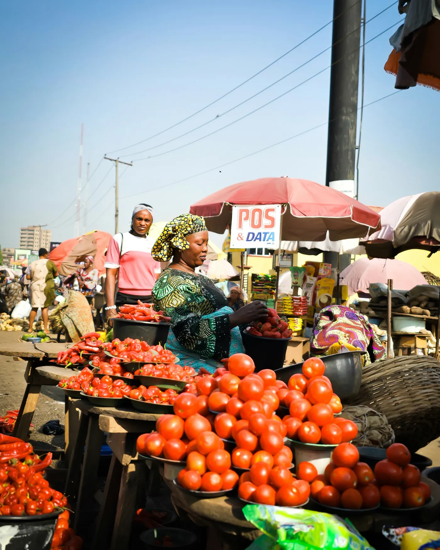 A tomato and pepper seller at her stall in a busy Nigerian market